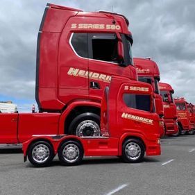 Small red truck replica beside actual lorry